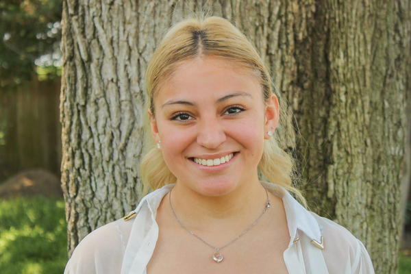 headshot of woman wearing necklace with tree in background