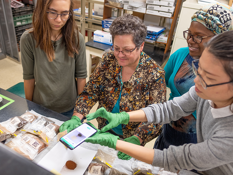 four people in science lab examining new app on phone